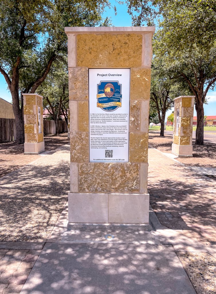 A set of pillars stands at the San Angelo NAACP Buffalo Soldier Memorial, honoring the all-Black regiments stationed at Fort Concho after the Civil War. The memorial is surrounded by plaques detailing their contributions to the city.